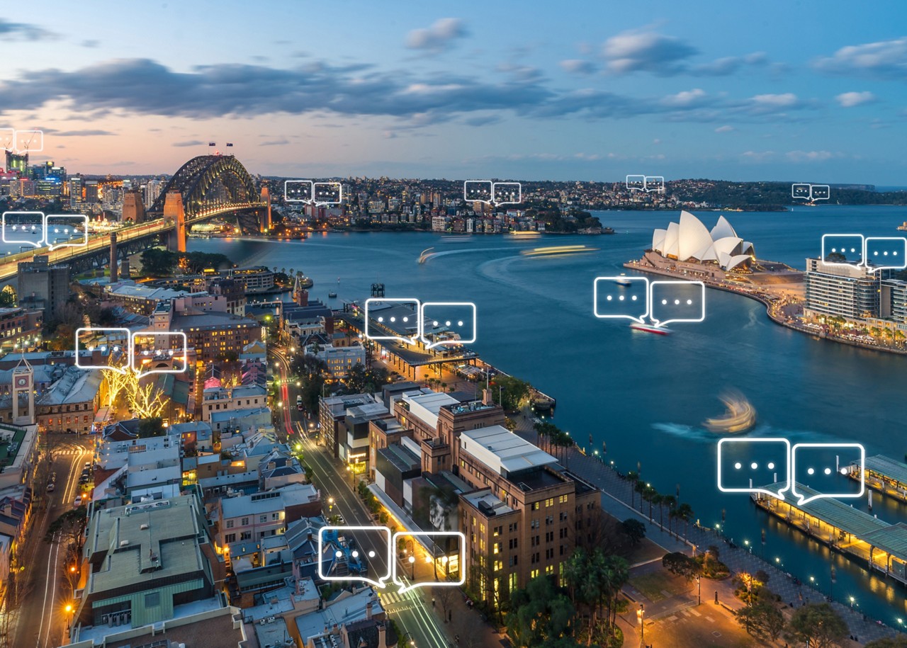 Horizonte de la ciudad de Australia al atardecer con burbujas de diálogo superpuestas que salen de varios edificios Horizonte de la ciudad de Australia al atardecer con burbujas de diálogo superpuestas que salen de varios edificios