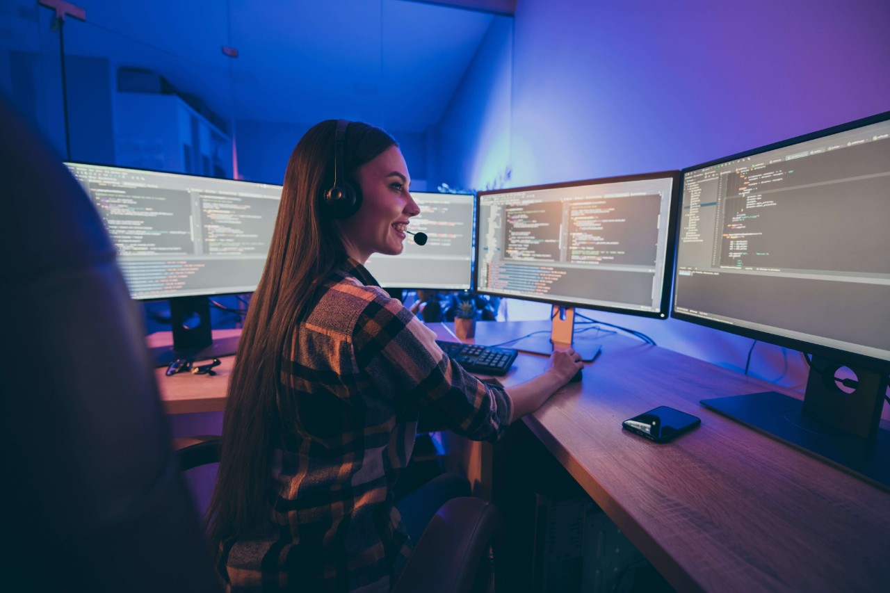 Turned photo of cheerful positive woman smiling toothily supporting clients customers in checkered shirt modifying security code Turned photo of cheerful positive woman smiling toothily supporting clients customers in checkered shirt modifying security code