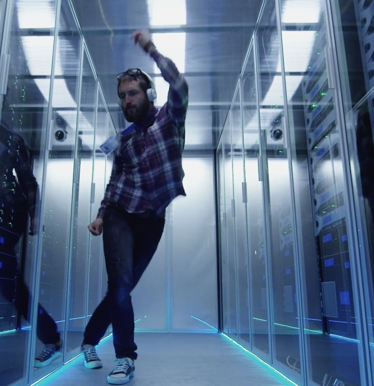 Man with headphones dancing in data center Man with headphones dancing in data center