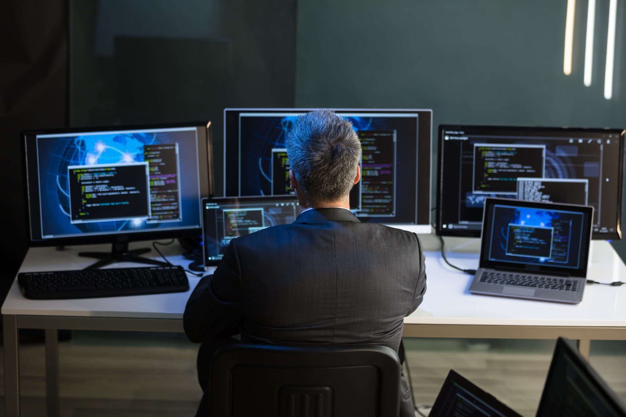 Businessman Looking At Multiple Computer Screens Businessman Looking At Multiple Computer Screens